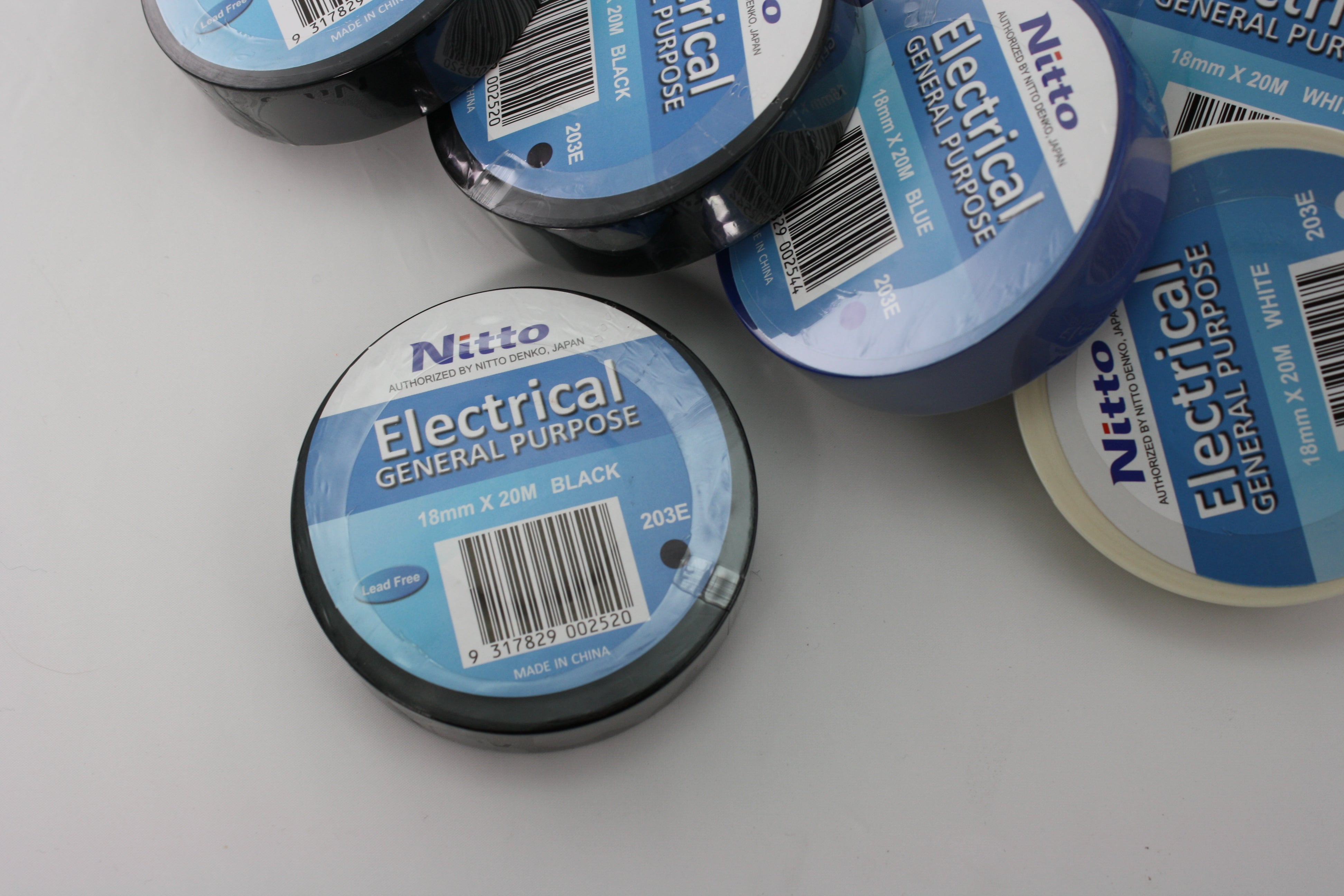 A close up of a roll of black Nitto electrical tape, with some other rolls in the outer frame of the image./